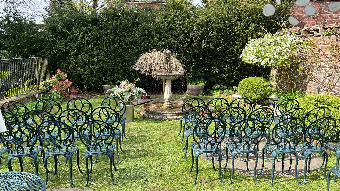 Chairs arranged for a handfasting ceremony around the fountain in The Silk House's walled garden