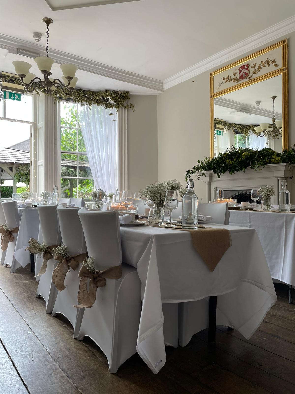 Wedding breakfast tables dressed with burlap chair sashes in daylight at The Silk House